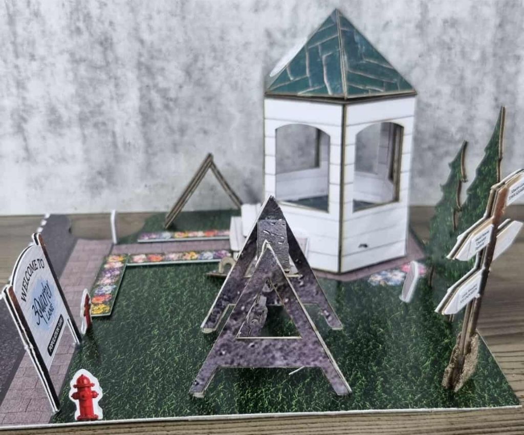 Miniature park diorama featuring gazebo, jungle gym, flower path, pine trees, and a welcome sign for 3Quarter Lane.