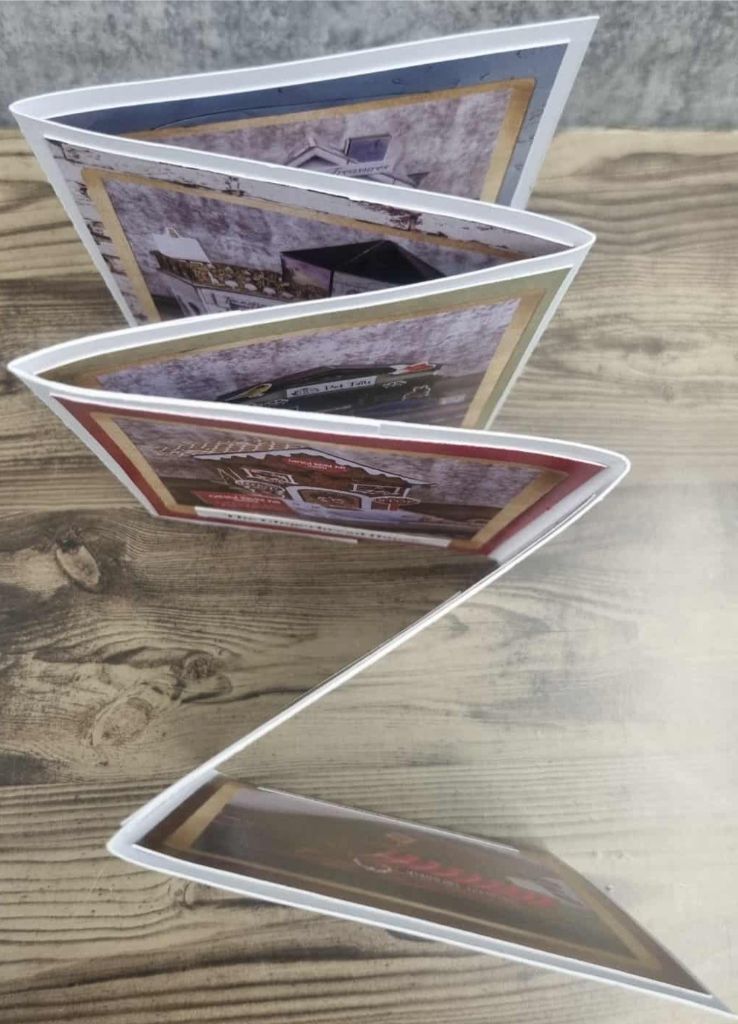 Zigzag-folded promotional booklet displaying miniature village buildings and signage for 3Quarter Lane.